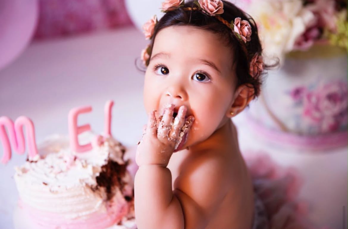 Bebê experimentando o bolo em cenário rosa durante ensaio Smash the Cake da Fotobella